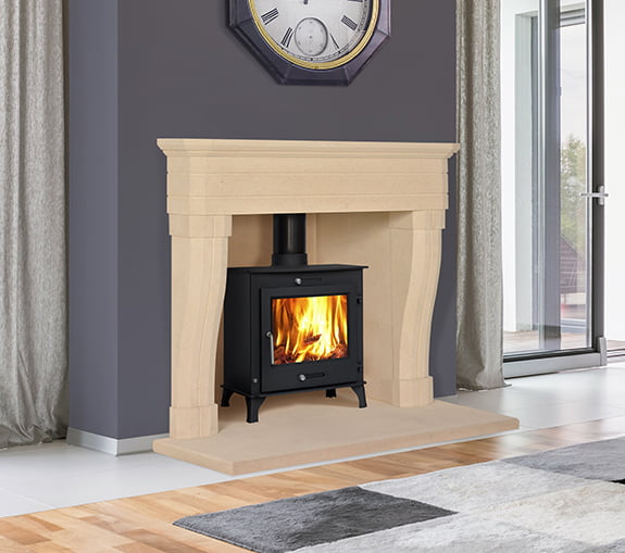 Large white stone fireplace with black log burner fire, Feature clock above fireplace, grey rug on floor, Sandridge Stone Fireplaces, Limestone, Bath Stone, Portland Limestone, Melksham, Wiltshire