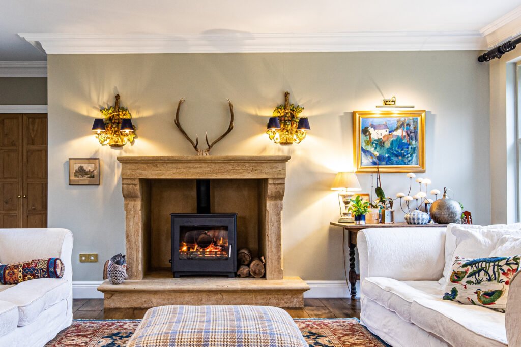 Luxury country living space, with sofas, wood panelled walls, bath stone fireplace with roaring fire, Sandridge Stone Fireplaces, Limestone, Bath Stone, Portland Limestone, Melksham, Wiltshire